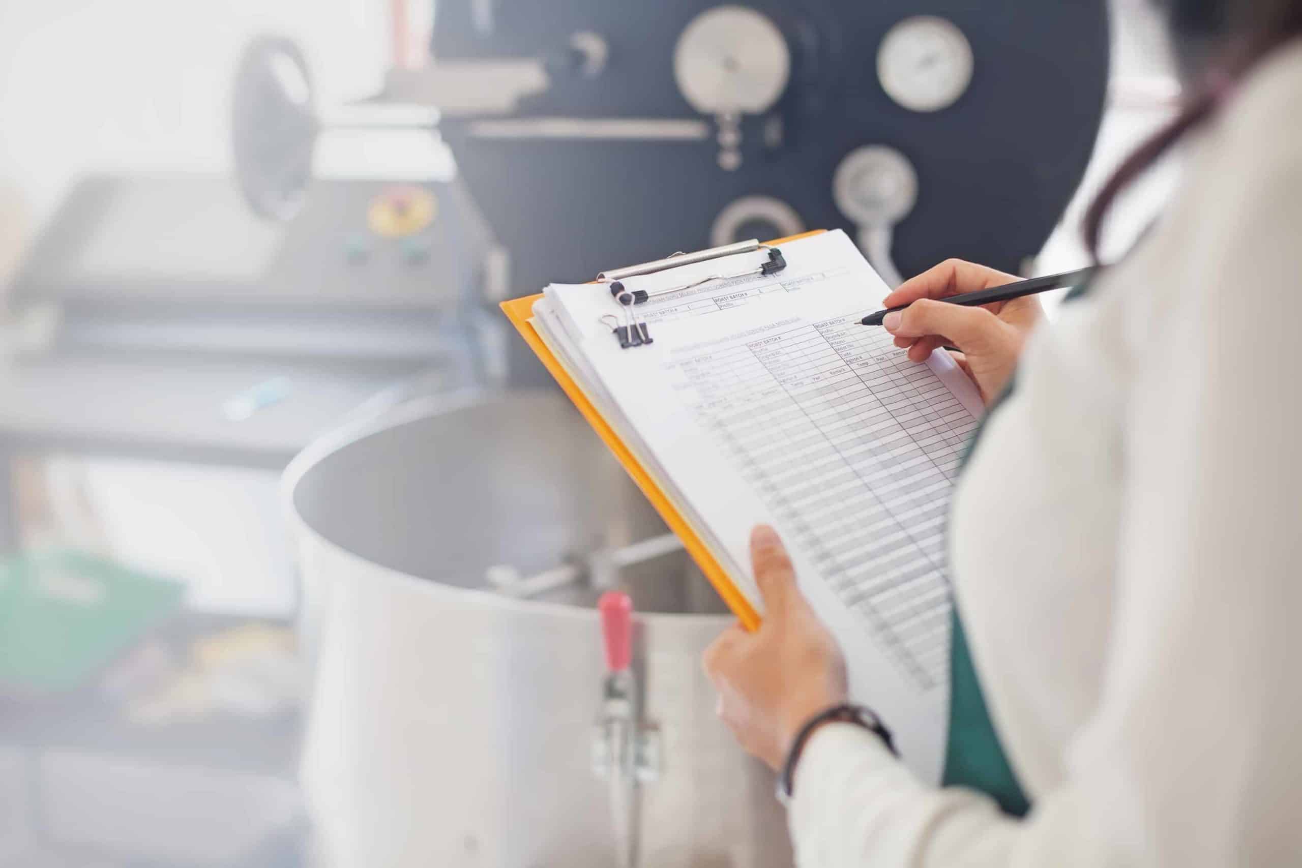 Healthcare professional recording data on clipboard.