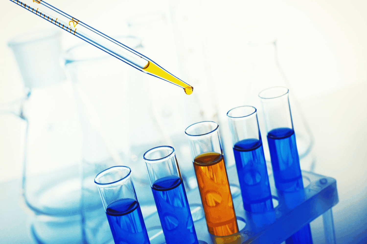 Pipette adding liquid to test tubes in laboratory.