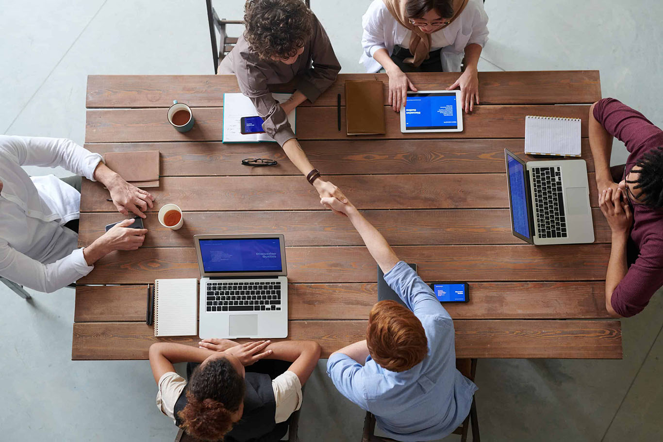 Team meeting with handshake over work table.