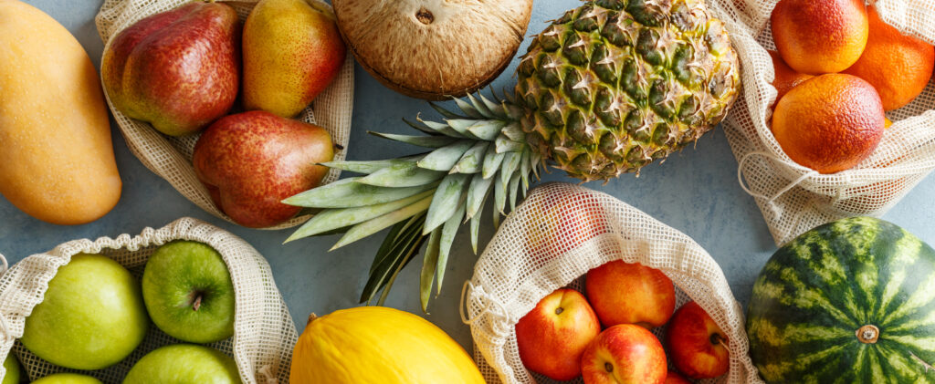 Variety of fresh fruits in reusable bags
