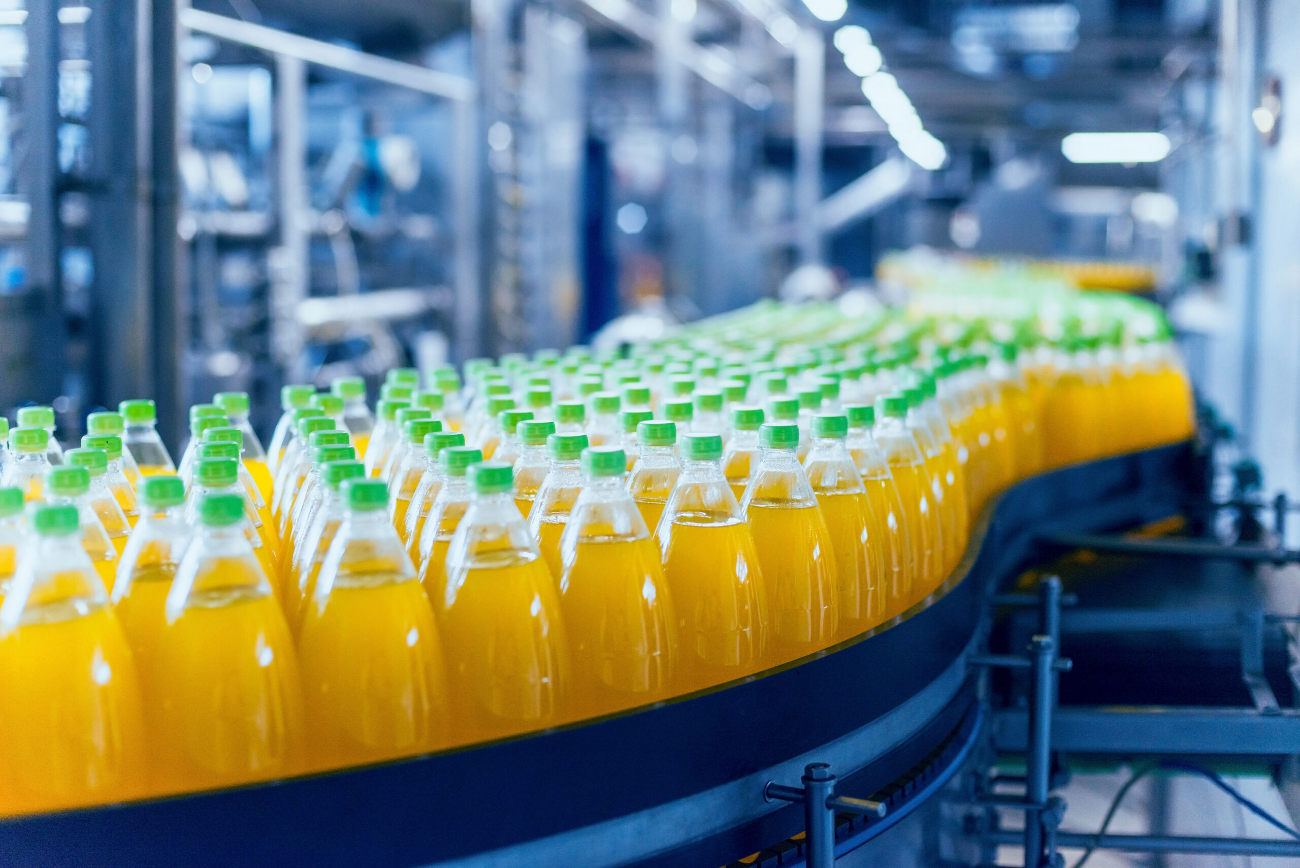 Orange beverage bottles being pushed through on a conveyer belt in a manufacturing facility
