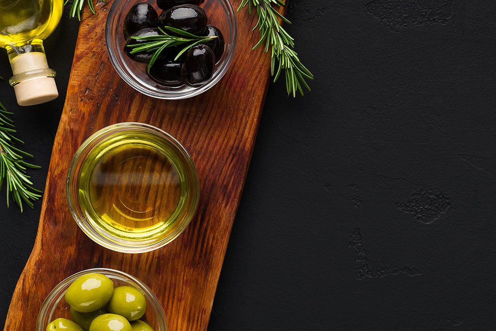 Olive oil and olives in bowls on cutting board