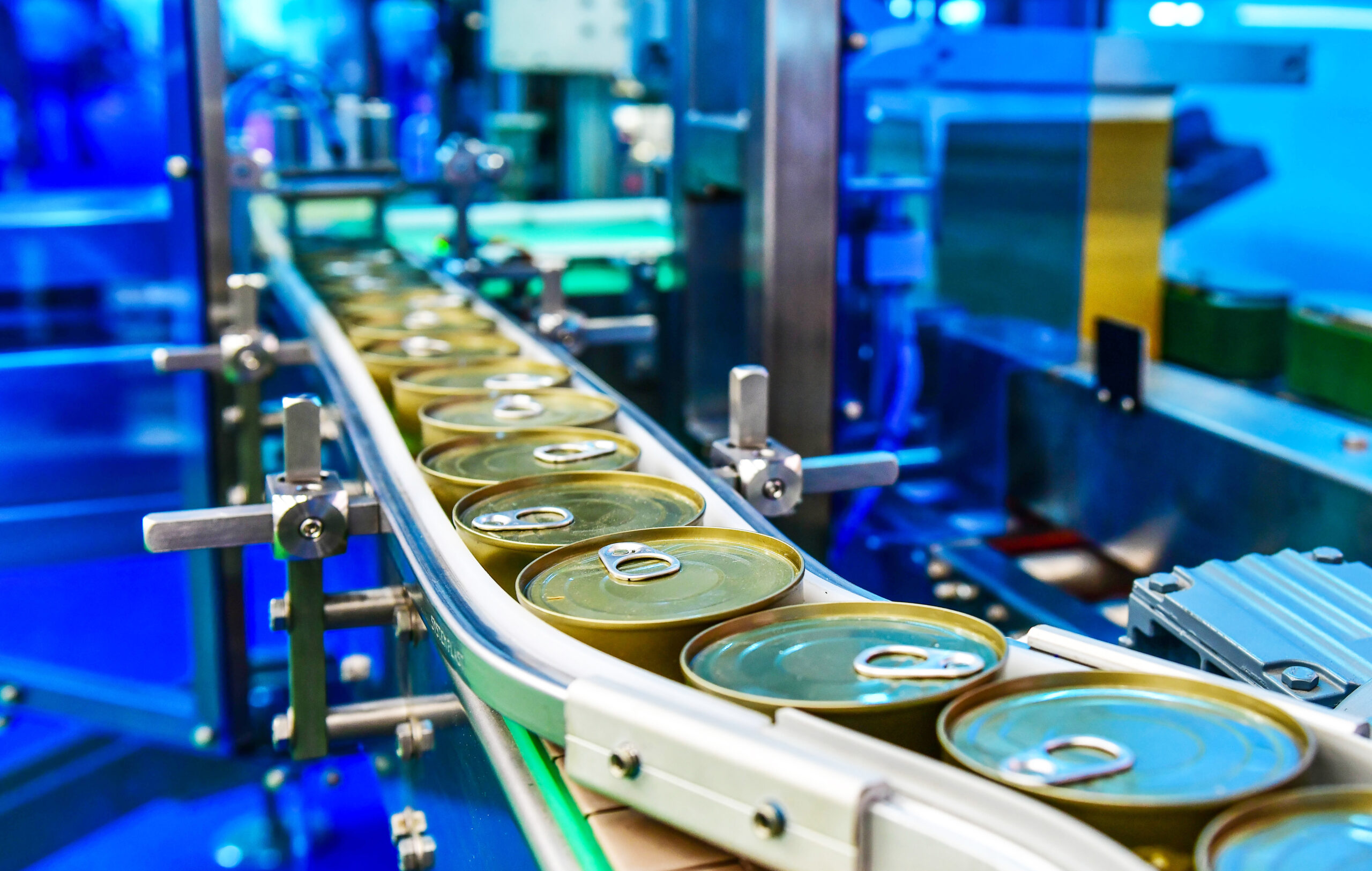 Metal food cans on an automated production line in a food processing facility.