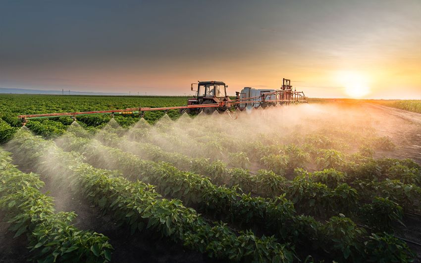 Image of tractor in field spraying pesticides